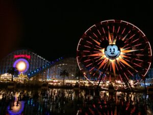 a ferris wheel and roller coaster at night with Disney California Adventure in the background