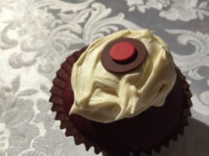 a cupcake with white frosting and a red circle on top