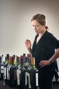 a woman standing next to a row of wine bottles