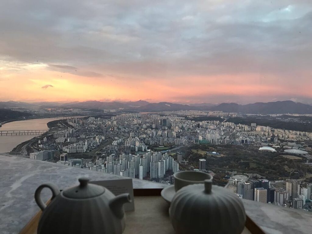 a tea set and cups on a table with a city in the background